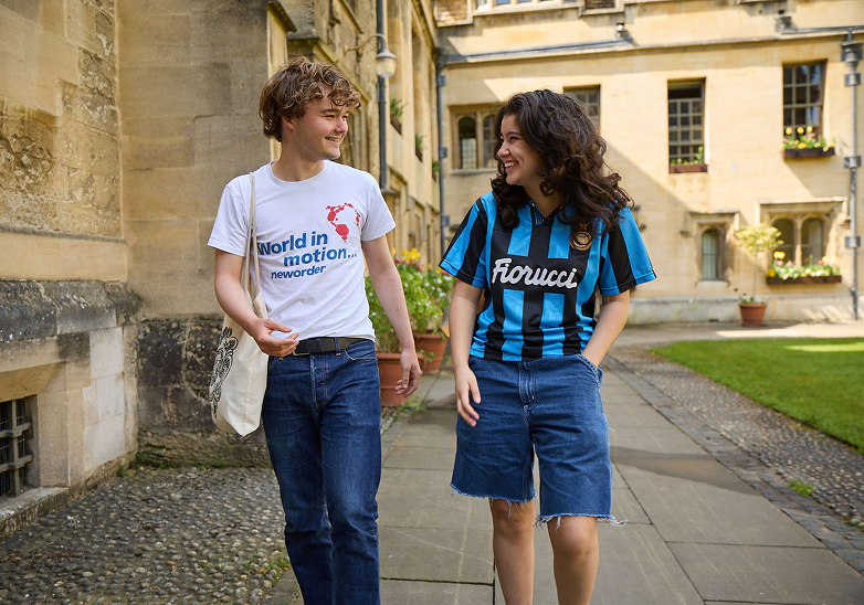 Two students walking together through the quad on a summer day