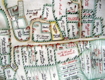 Detail from an old hand-drawn and coloured map showing fields, buildings, and handwritten names of landholders
