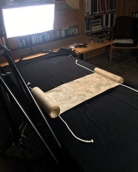 Historical manuscript scroll being photographed under studio lighting in a university library for digital preservation