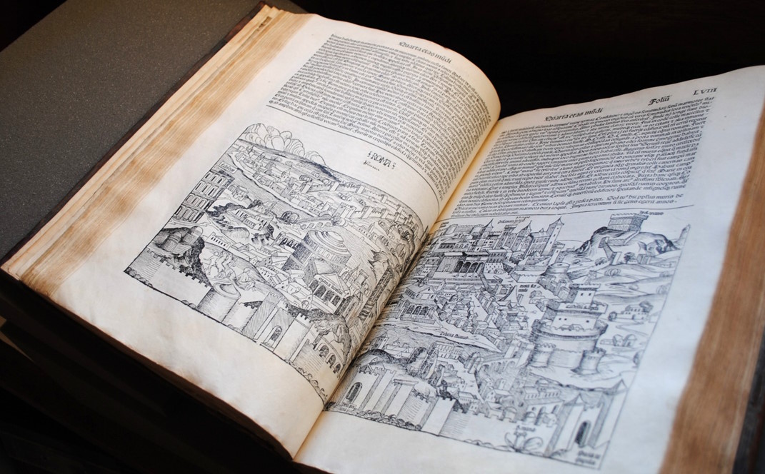 Open antique book displaying woodcut illustrations of an ancient cityscape with Latin text on both pages