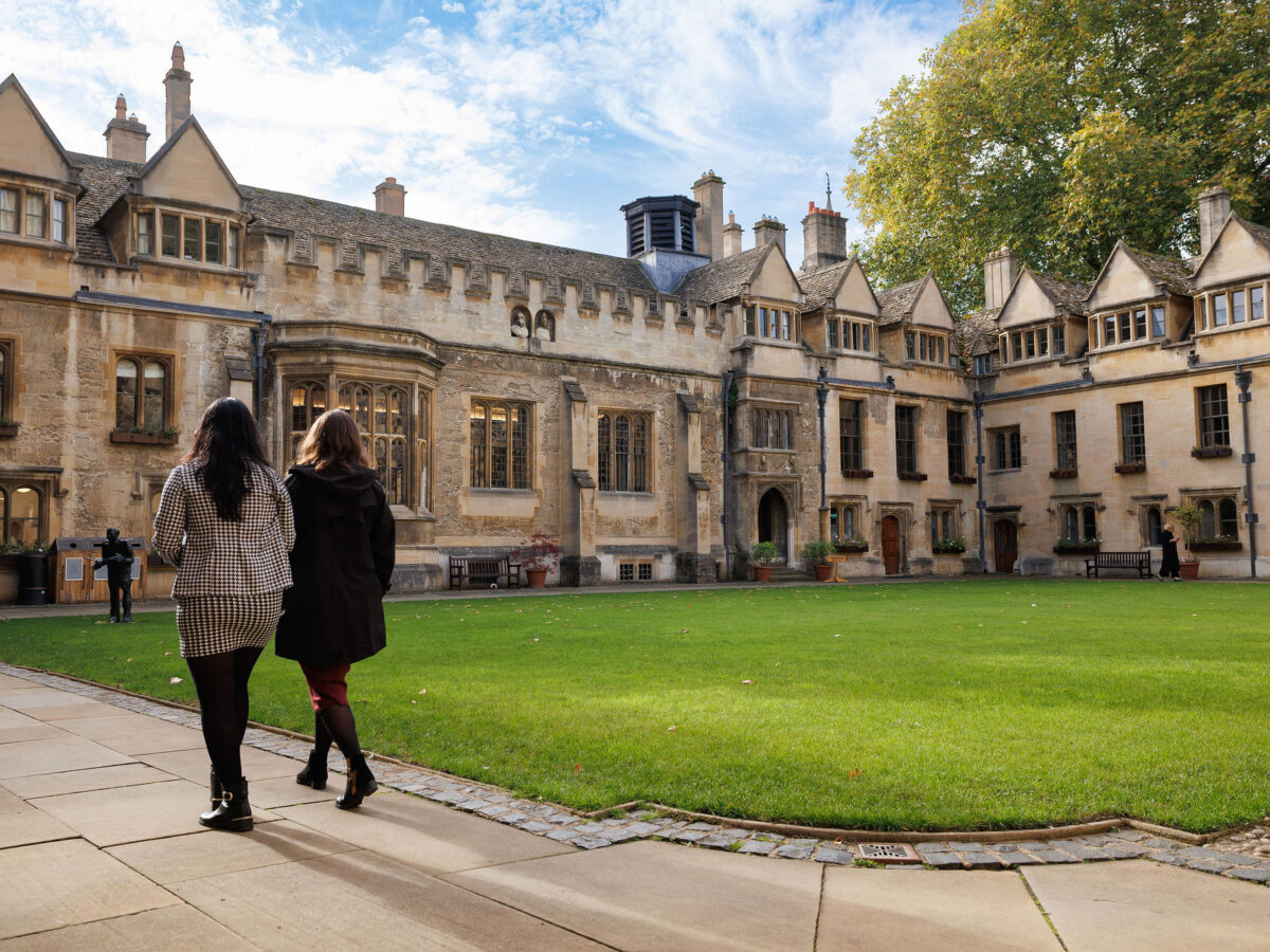 Two people walking through the Brasenose quad