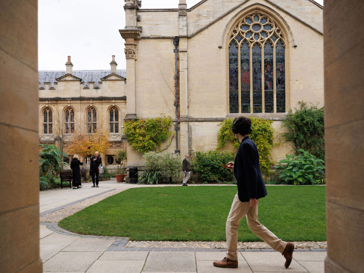 Person wearing headphones walking across the quad