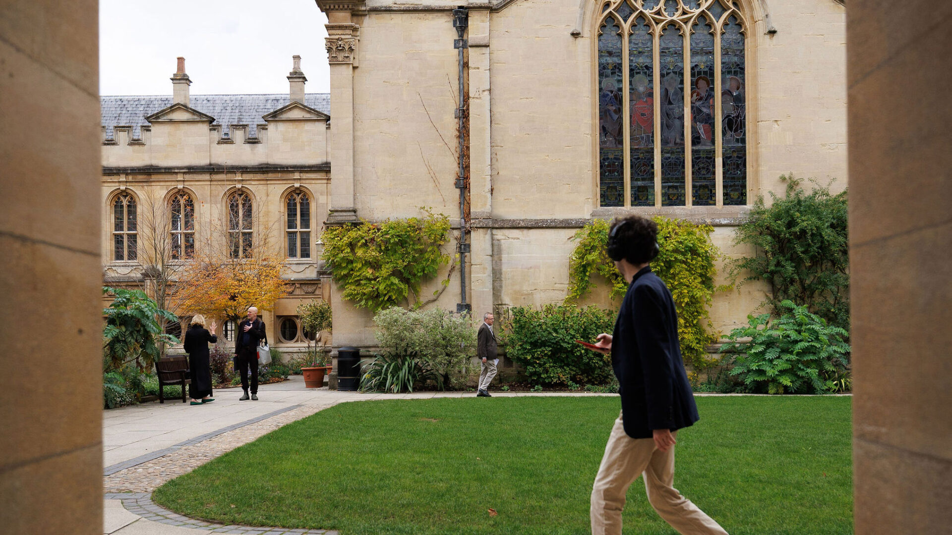 Person wearing headphones walking across the quad