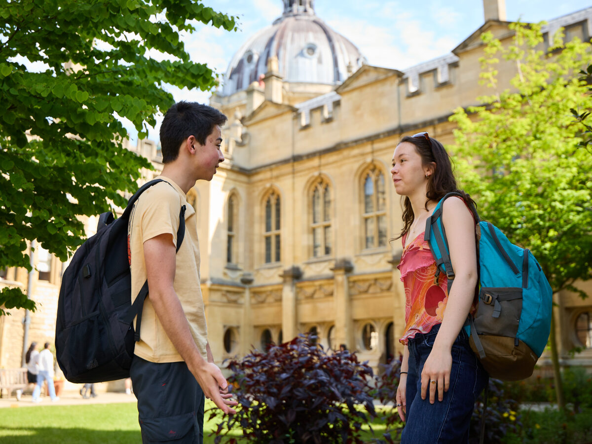 Two students standing outdoors talking in the quad