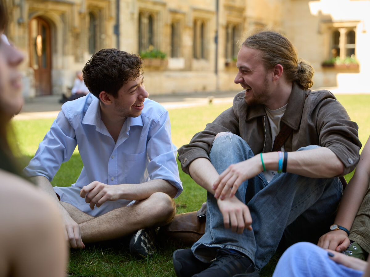 Two students sat in the Brasenose quad laughing while facing each other
