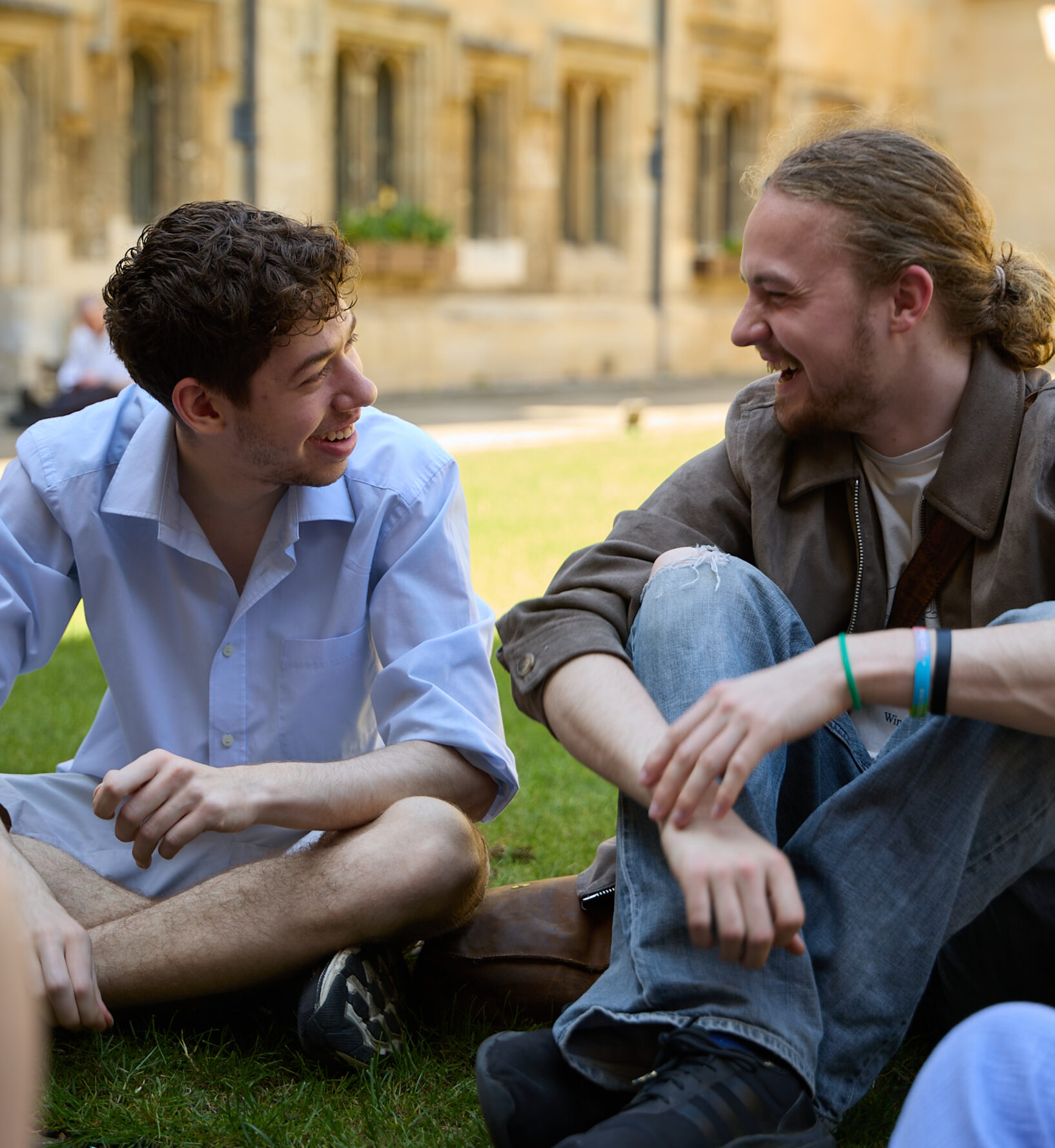 Two students sat in the Brasenose quad laughing while facing each other