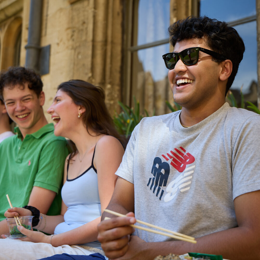Group of students sitting outdoors together, laughing and talking