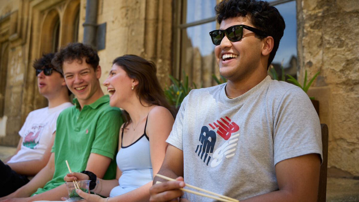 Group of students sitting outdoors together, laughing and talking