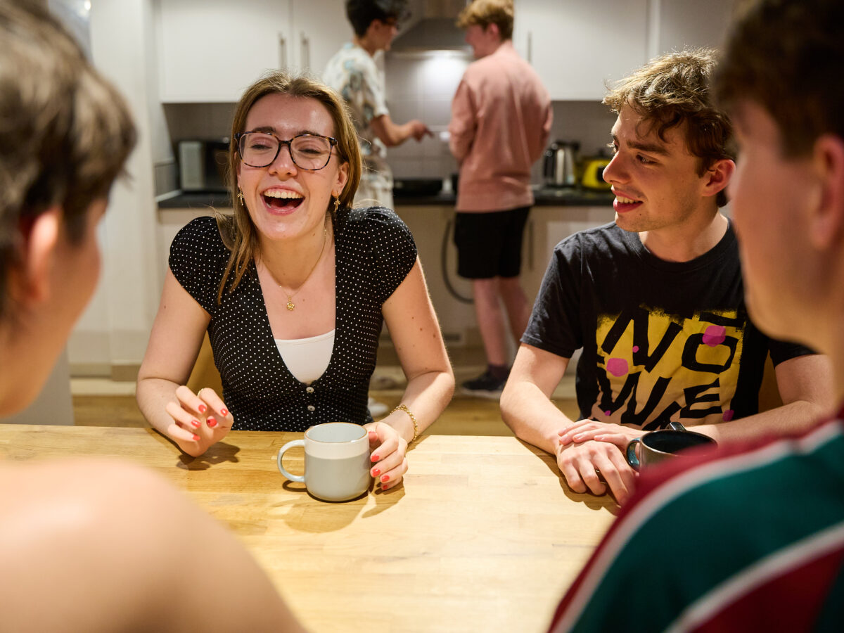 People sitting indoors at a table, smiling and talking.