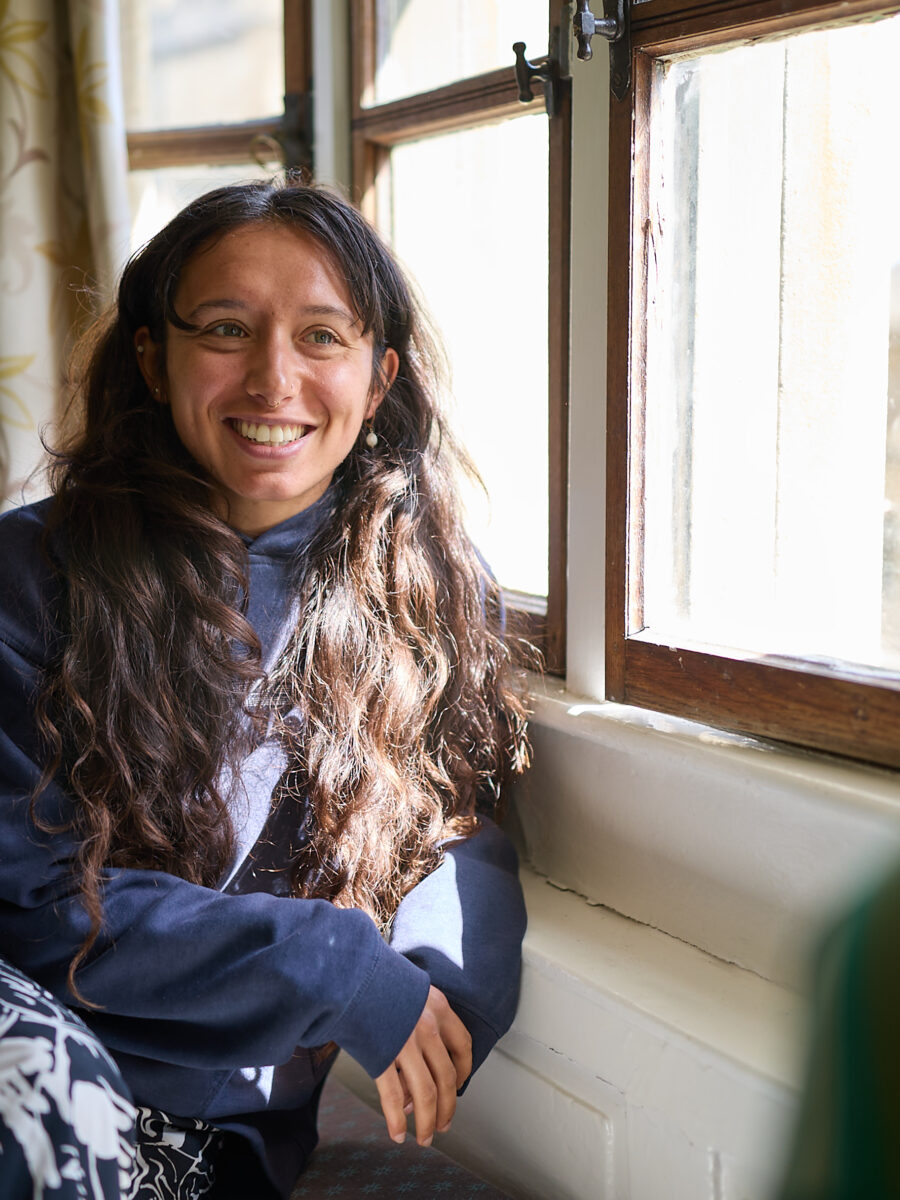 Person sitting indoors by a window, smiling