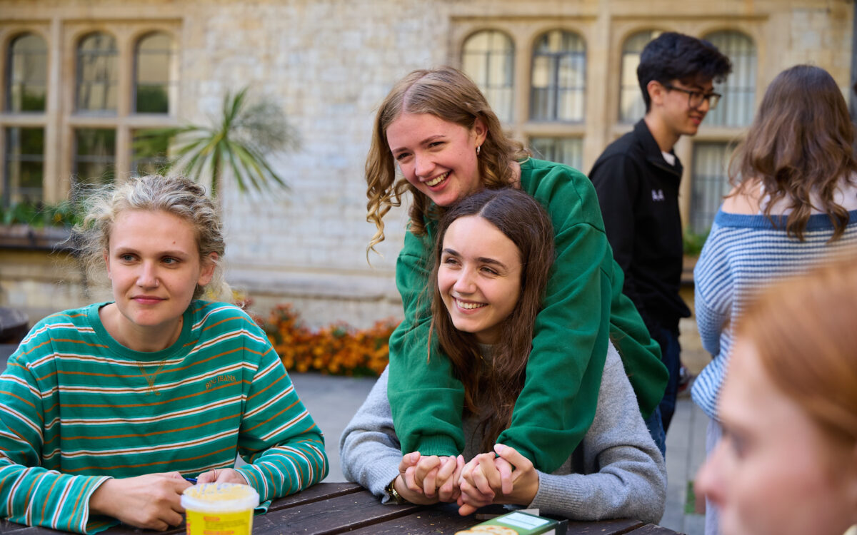 Group of people sitting outdoors together at a table in a college courtyard