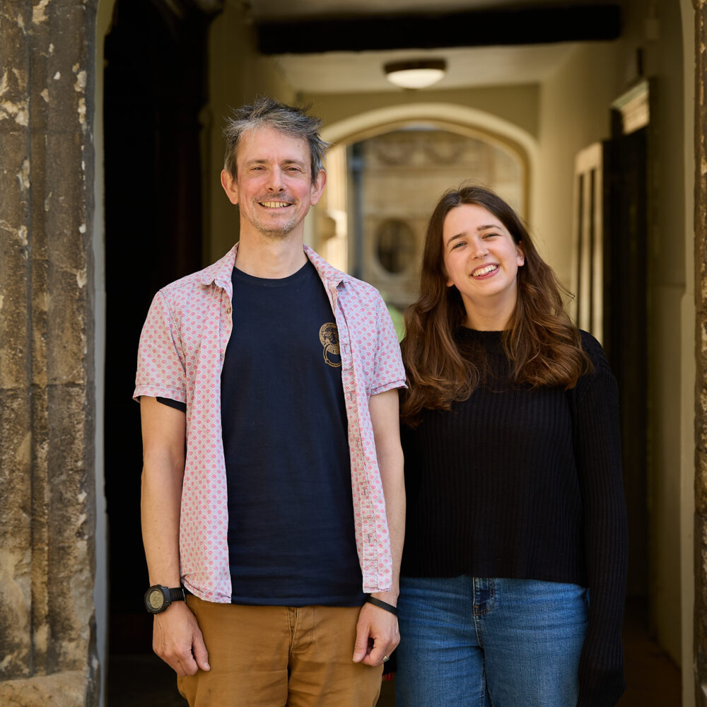 Two people standing together in a college doorway, smiling.