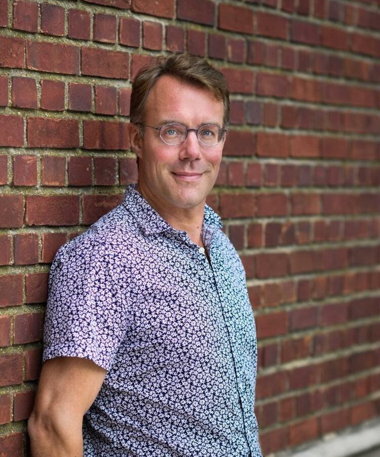 Portrait of a man standing outdoors against a brick wall