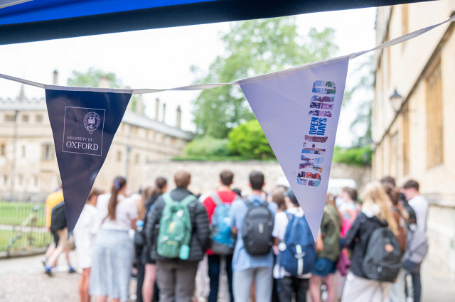 A group of prospective students gather behind Open Days bunting