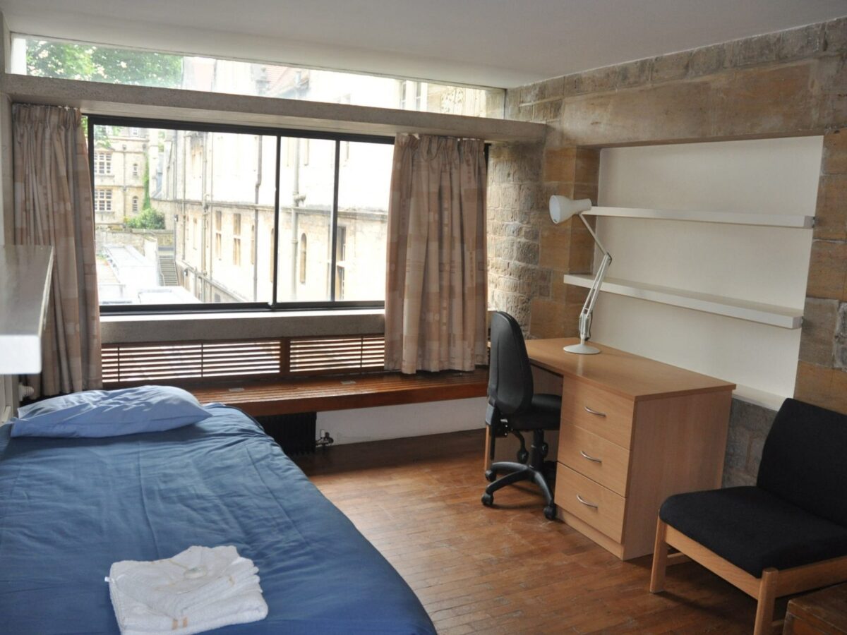 Interior view of a student bedroom with bed and desk