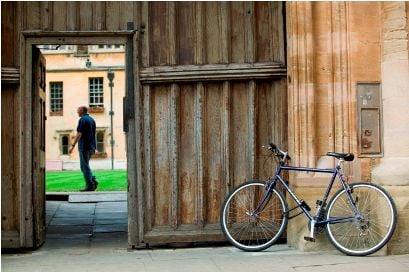 Bicycle parked beside a stone college wall