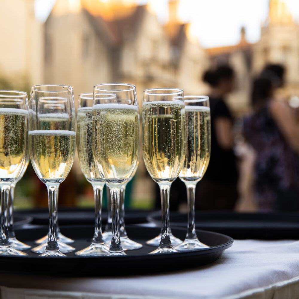 Glasses of sparkling wine arranged on a tray at a social event