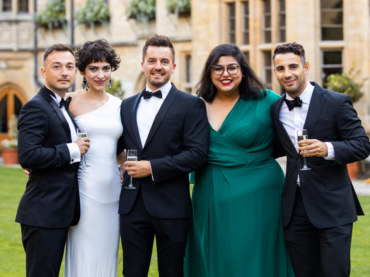 Group of 5 alumni in black tie and gowns