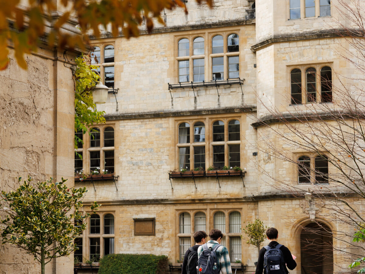 People walking through a college courtyard surrounded by historic buildings on the quad