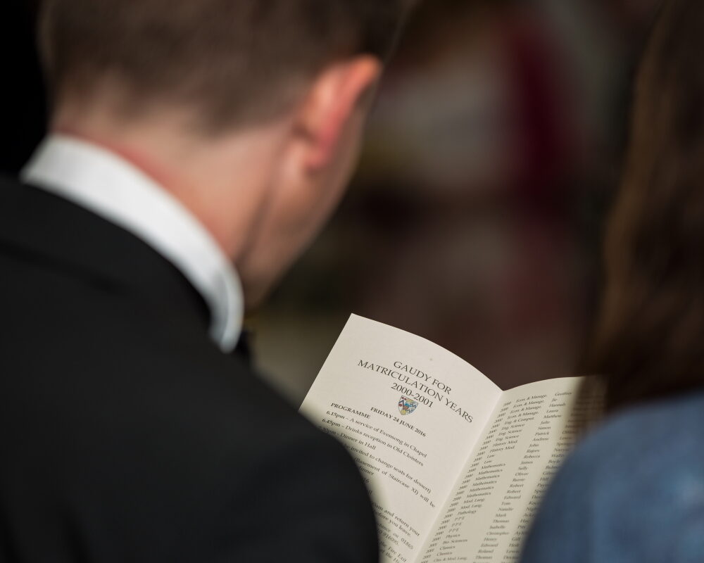 Person holding a Gaudy 2000-2001 booklet open, viewed from behind