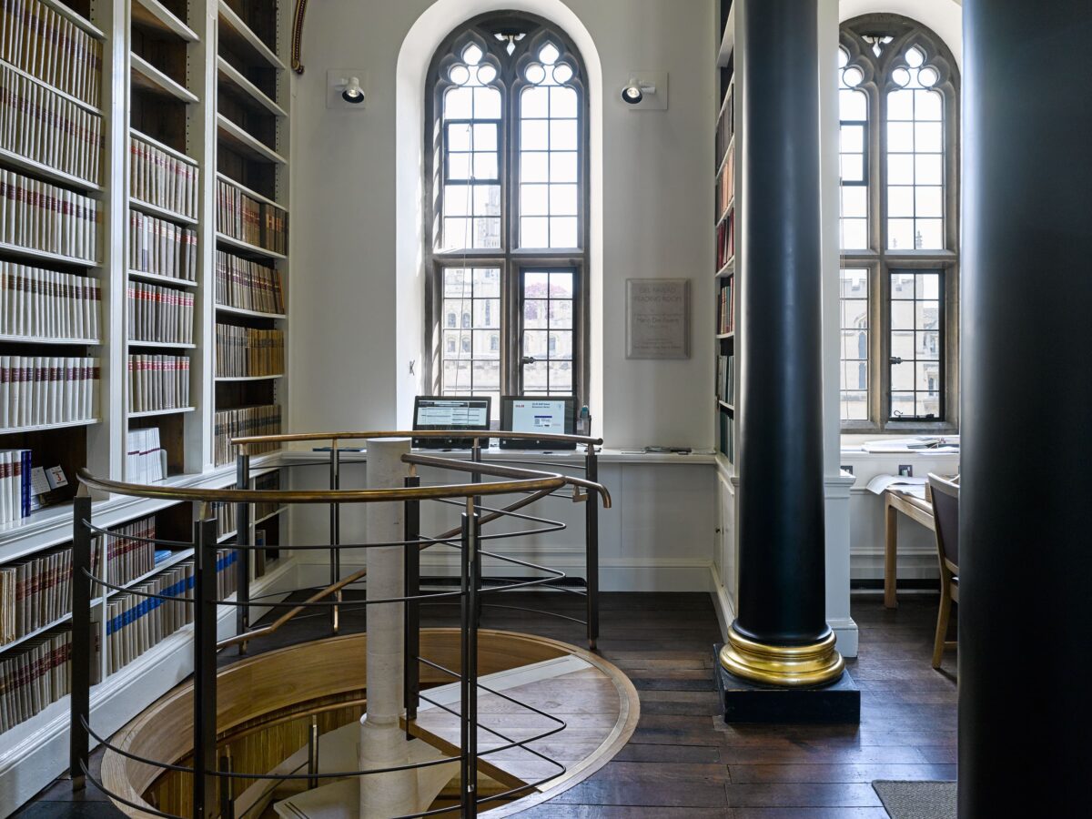 The spiral staircase up to the Main Library, with arched windows and shelving