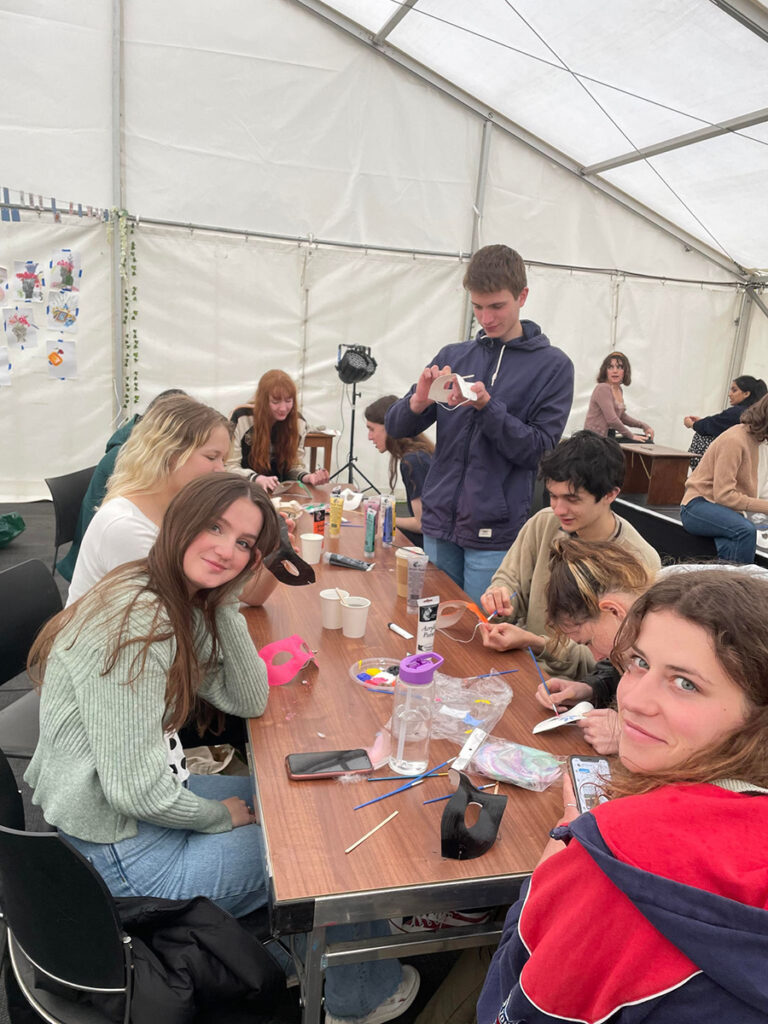 Students taking part in a craft activity together at a table in a marquee