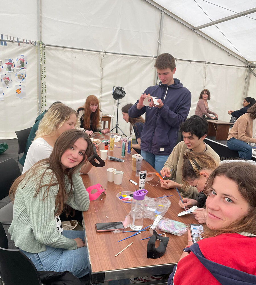 Students taking part in a craft activity together at a table in a marquee