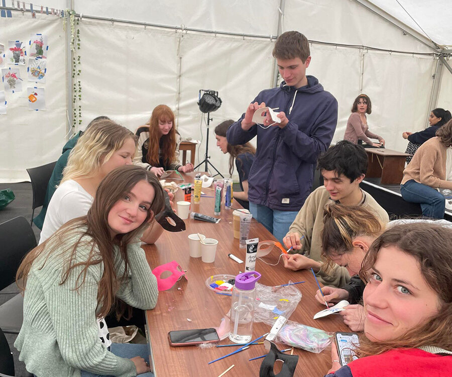 Students taking part in a craft activity together at a table in a marquee