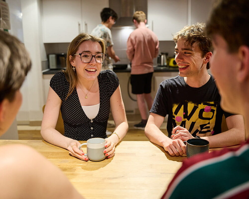 Students chatting together around a table in a shared kitchen