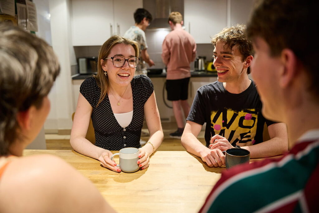 Students chatting together around a table in a shared kitchen