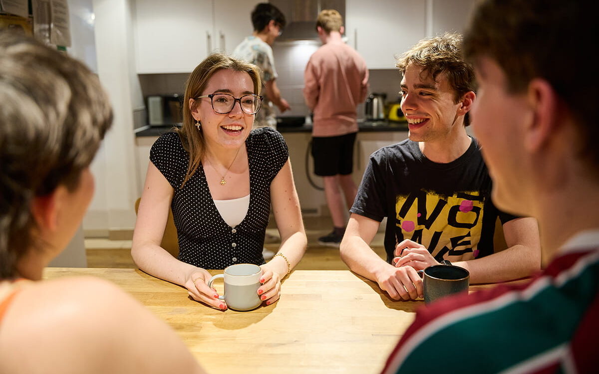 Students chatting together around a table in a shared kitchen