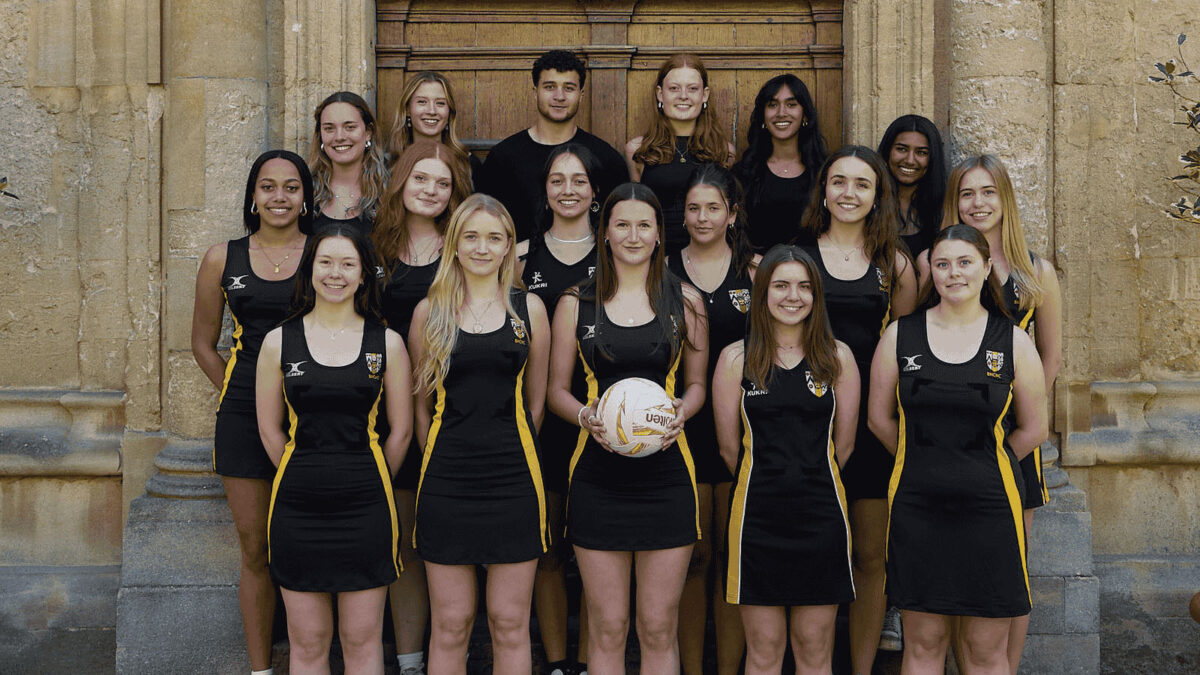 College netball team standing outdoors in team kit, posing for a group photo.