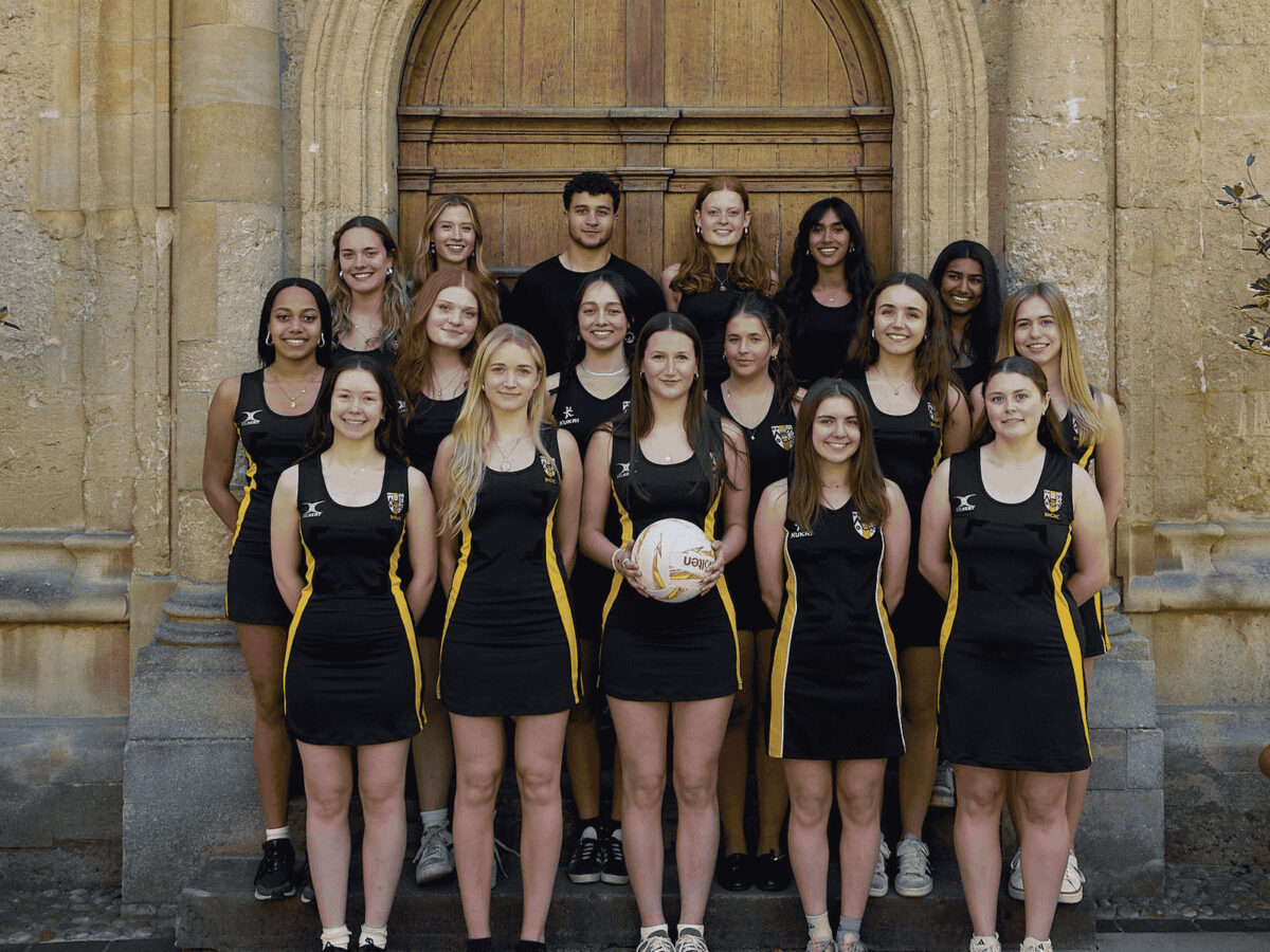 College netball team standing outdoors in team kit, posing for a group photo.