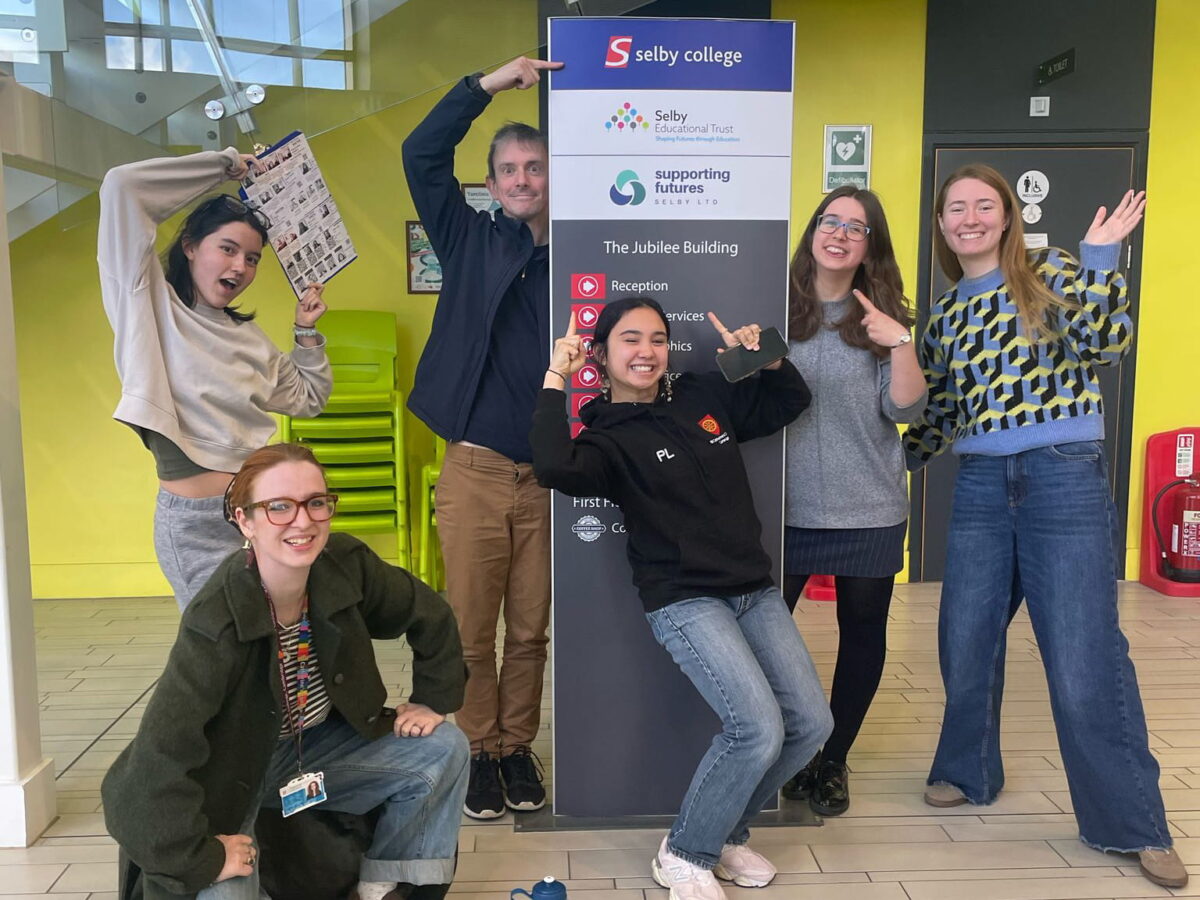 Outreach team posing beside a Selby College sign inside the Jubilee Building
