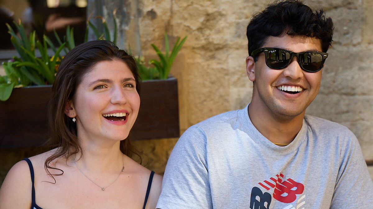 Two students sitting together on a bench in the quad