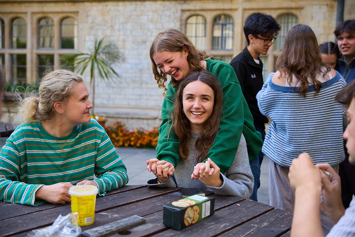 Students spending time together and talking at an outdoor table on the college quad