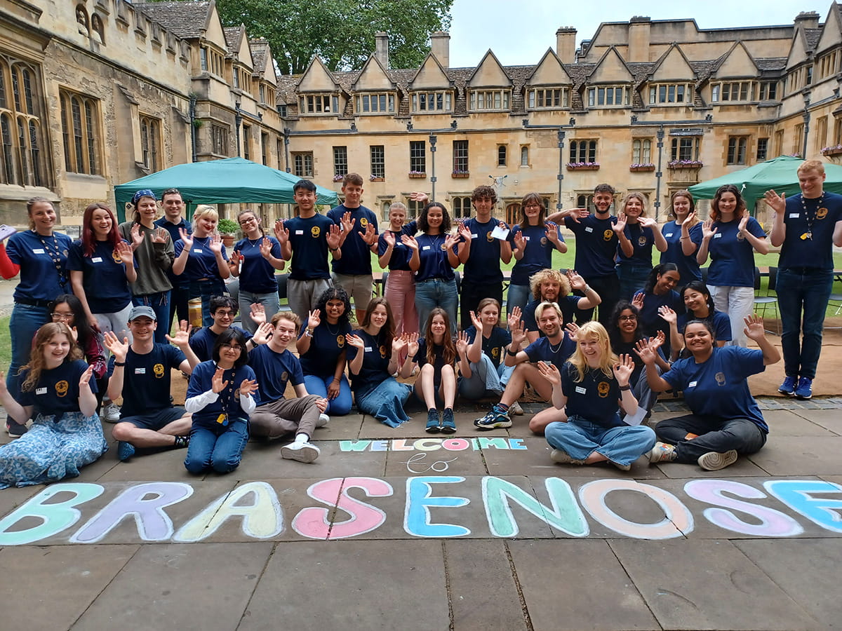 Welcome to Brasenose’ written in chalk on the ground in a college quadrangle, with students gathered behind.