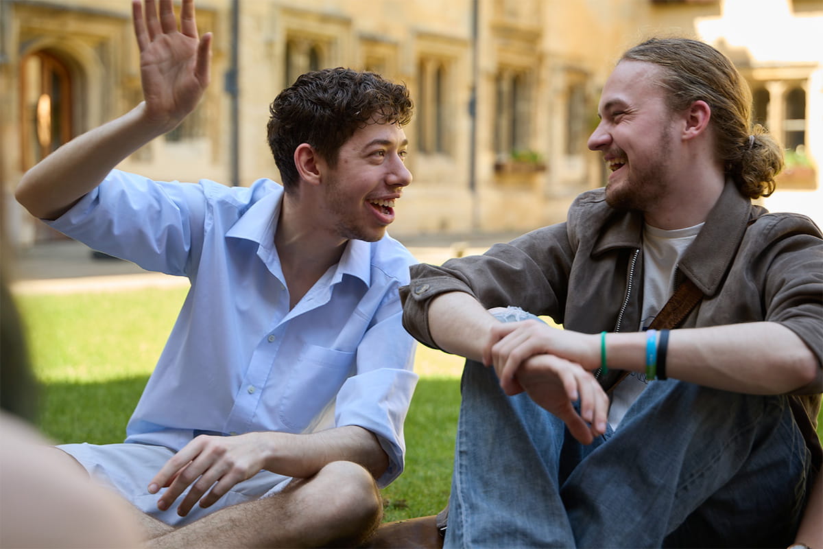 Two people sitting outdoors, talking and smiling in the college quad