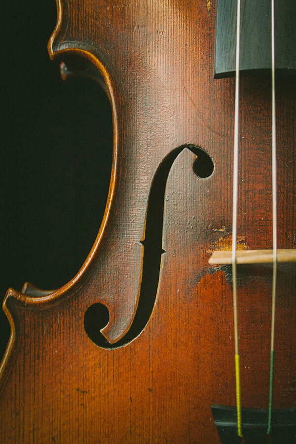 Close-up detail of a violin’s wooden body, showing the curved sound hole and strings