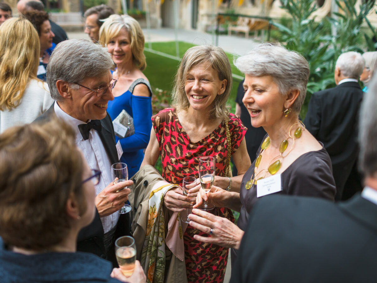 a group of alumni wearing black tie and holding champagne flutes